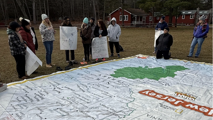 Teachers use a large New Jersey map to examine climate equity patterns and regional climate impacts while developing place-based climate lessons.