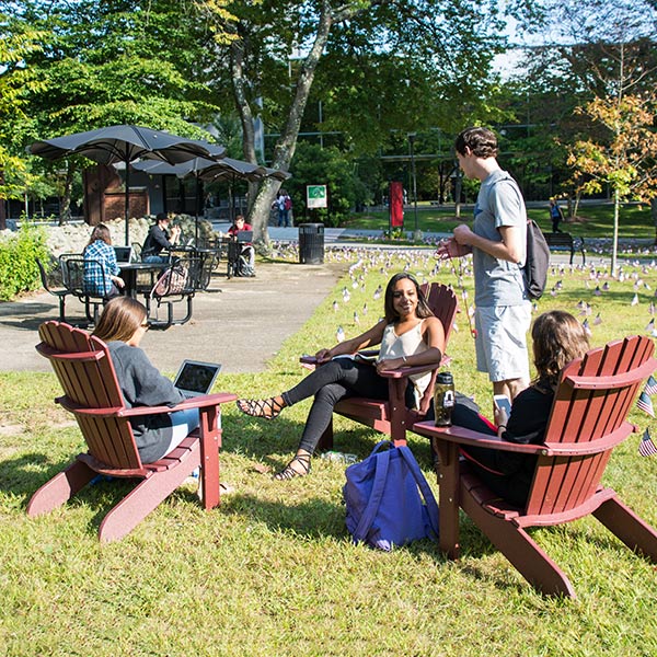 Students sitting in maroon Adirondack chairs talking with each other