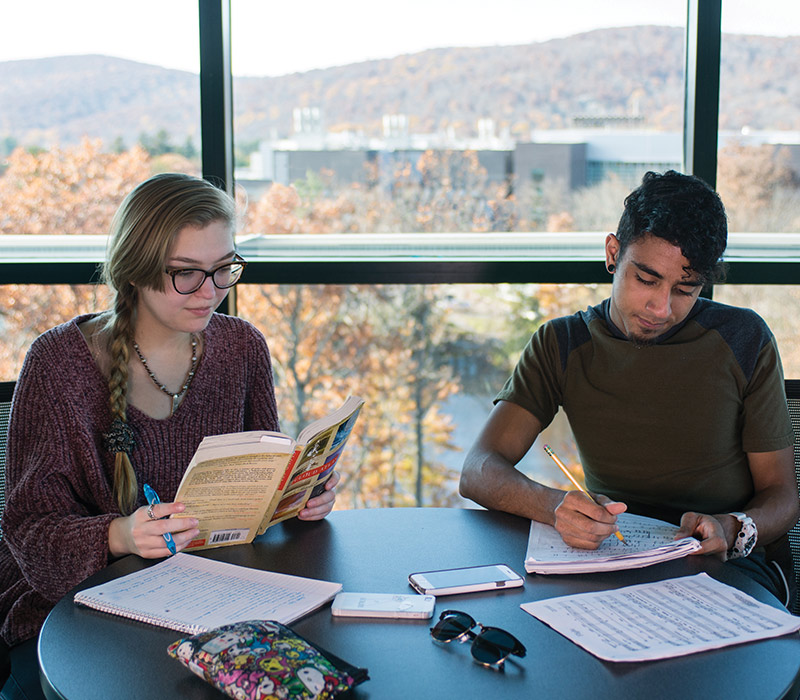 Ramapo Students with papers inside with a fall outdoor view