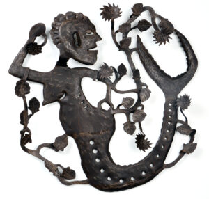 A mermaid of metal with tree-like growths protruding from tail at various points.