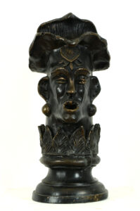 Bronze sculpture of a head. The face has an open mouth, and the ears feature large circular earrings.