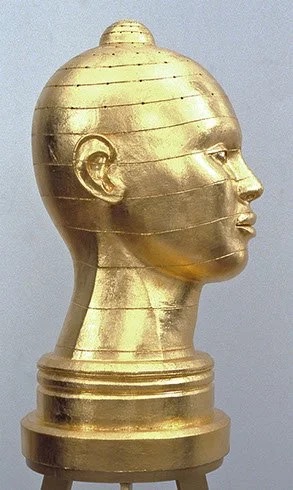 A golden statue of a woman's face in profile.