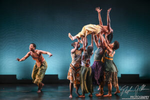 4 Dancers lifting someone, one dancer out in front.