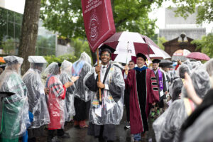 Students wearing regalia during Ramapo College's 2025 Arching Ceremony on a rainy day