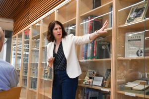 Christina Connors points to a particular section of books with bookshelves behind her