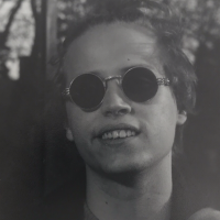 Rob Lenza Headshot, he is wearing circular sunglasses