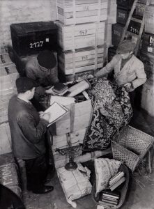 Black and white picture of Jewish workers sorting Jewish artifacts in Prague