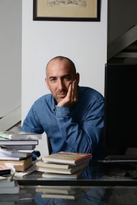 Picture of Dr. Ataria wearing a blue shirt, sitting by books