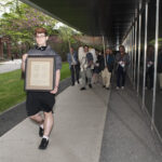 Ramapo student Seth Richardson leads our procession with a framed certificate from the Memorial Scrolls Trust.