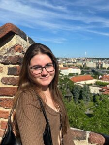 Picture of Maddie Zech by a brick wall overlooking a German city.