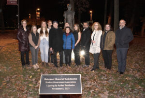 Ramapo affiliated people gathering around a statue with a new plaque in the foreground.