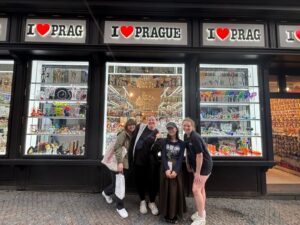 Four students standing in front of a souvenir store marked with "I *heart* Prague"