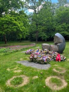 Picture of a memorial. A shattered sphere made out of concrete with red, white, and blue flowers.
