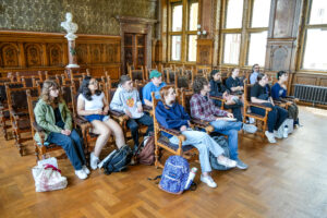 Students in a beautiful ceremonial hall. Sitting in chairs for a lecture.