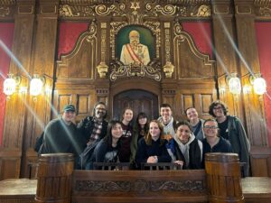 Kafka Room in the Jewish Town Hall. Students are gathered under a painting of HRE Franz Josef behind a heavy wooden dais.