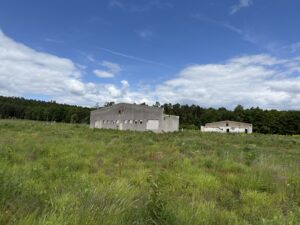Concrete walls in the distance across a grassy field.