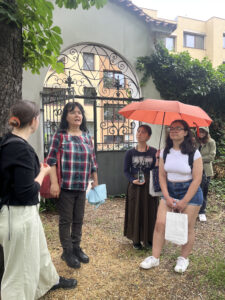 Students, one with an umbrella, inside a gated green space.