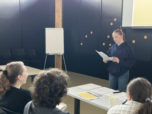 Student reads from a paper in front of a class