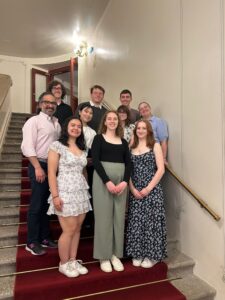 Students posed on stone stairs covered by a red carpet.