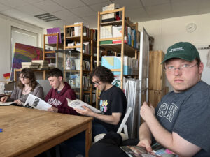 Three students at a wooden table in front of filled wooden bookshelves