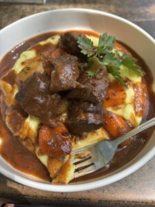 A plate of colorful Czech gulash with dumplings peaking out.