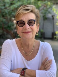 Picture of Marianne Hirsch in a white shirt with sun glasses and earings.