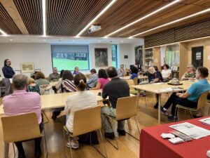 Beautiful classroom with four rectangular tables, around which sit some 20+ senior citizens. Dr. Labendz can be seen standing and speaking from the corner.