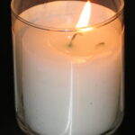 A lit yahrzeit candle against a black backround.