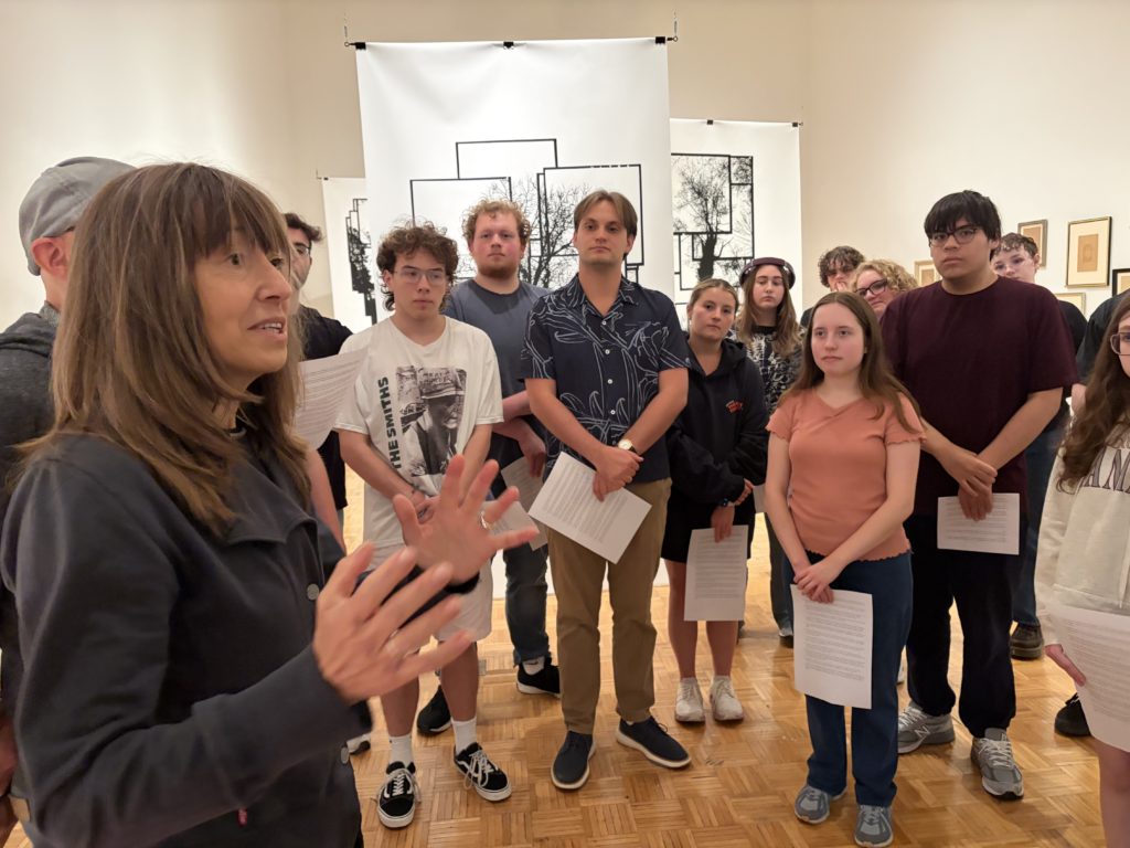 Students standing in an art gallery listening to a speaker.