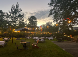 The Grove at Ramapo lit with bistro lighting and picnic tables set for the keynote night.