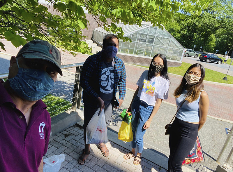 Rajesh Adhikari and three students wearing masks showing the food that was collected