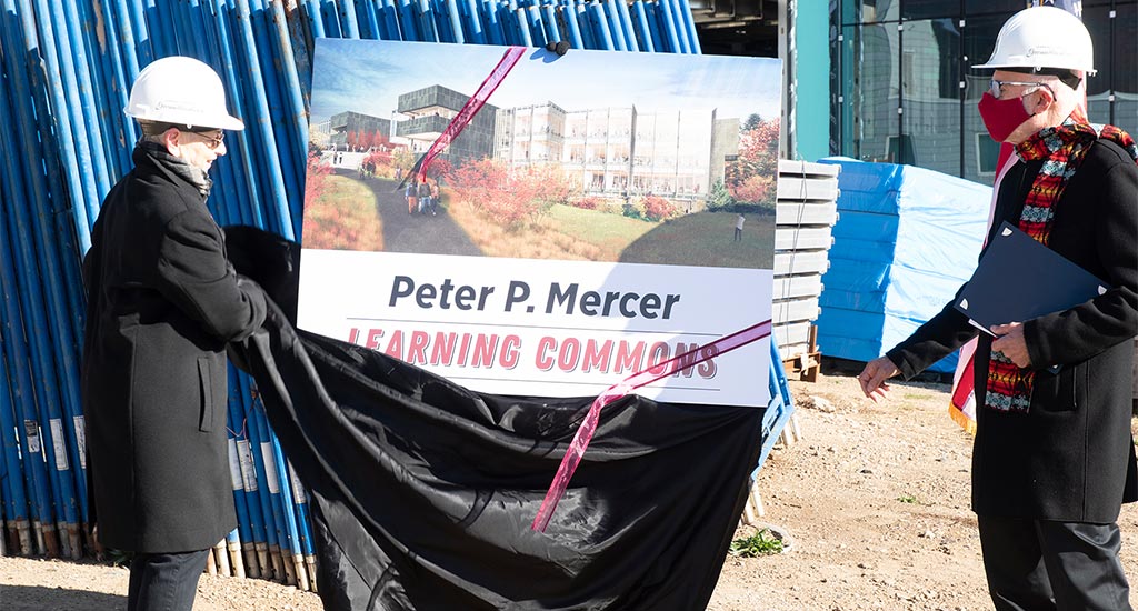 Two people unveiling the sign for the new Mercer Commons