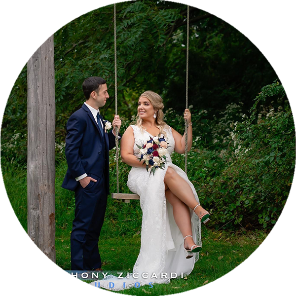 man in suit looks at his new bride sitting on a swing