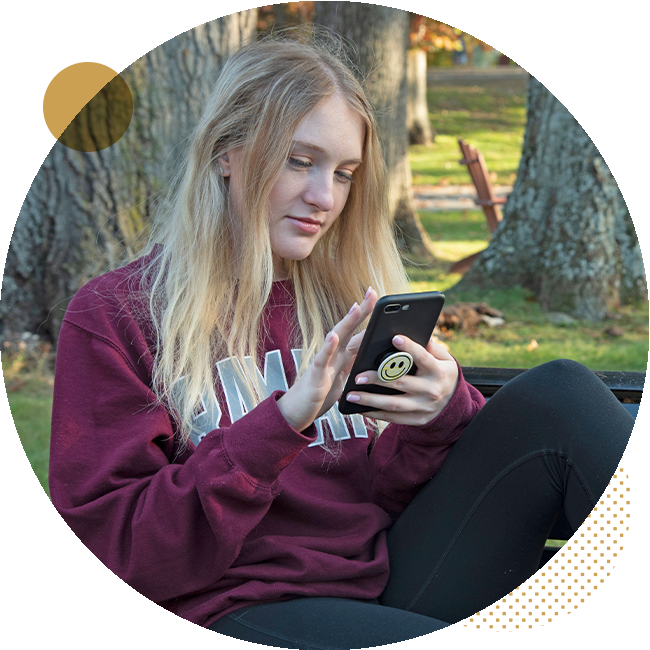 Student sitting on a bench looking at her phone