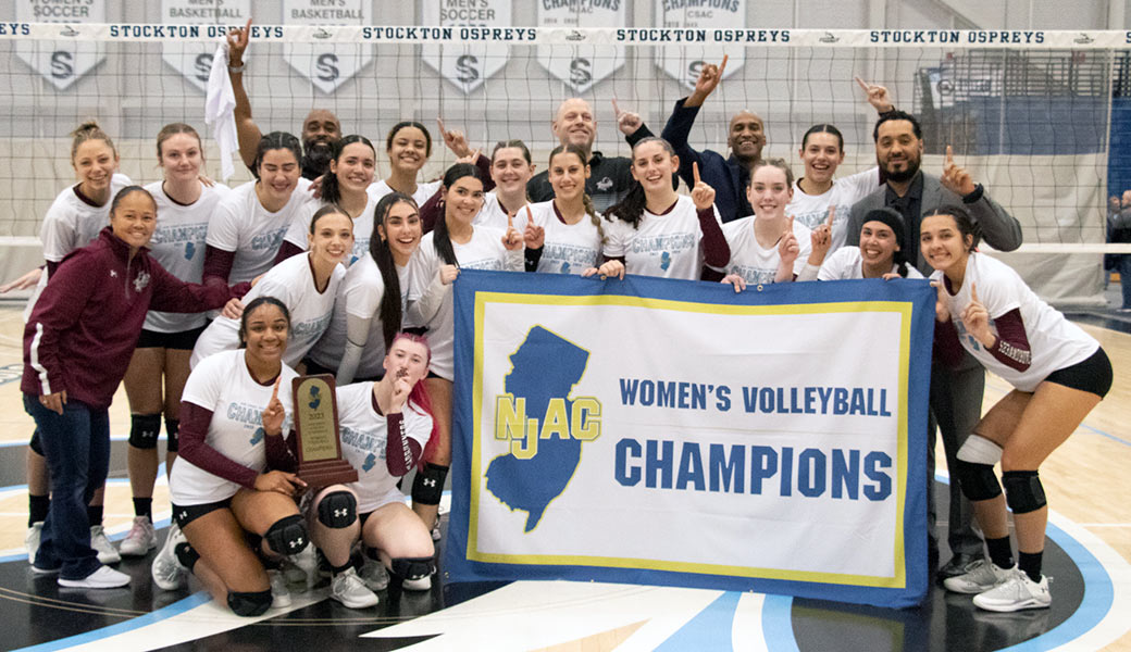 Ramapo College Women's Volleyball team holding NJAC Champions banner.