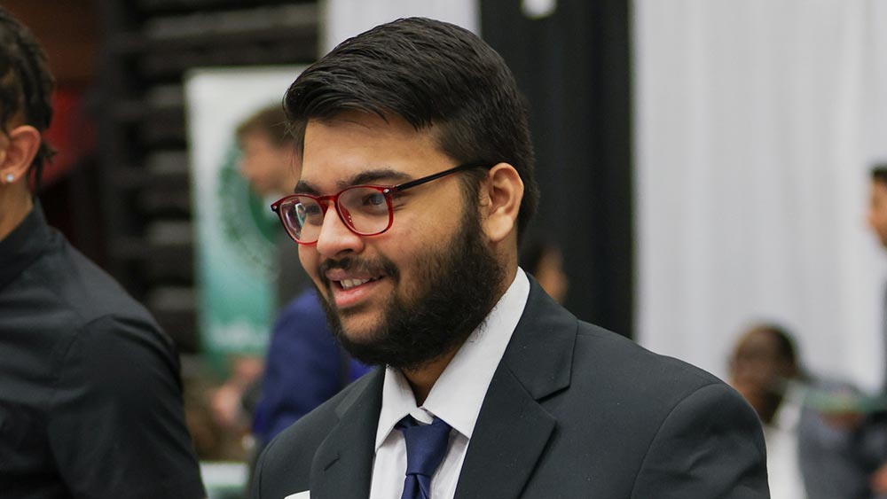 A-Young-Alumni-Survival-Guide_fall2025-home Ramapo College student at the Career Fair on campus wearing a suit