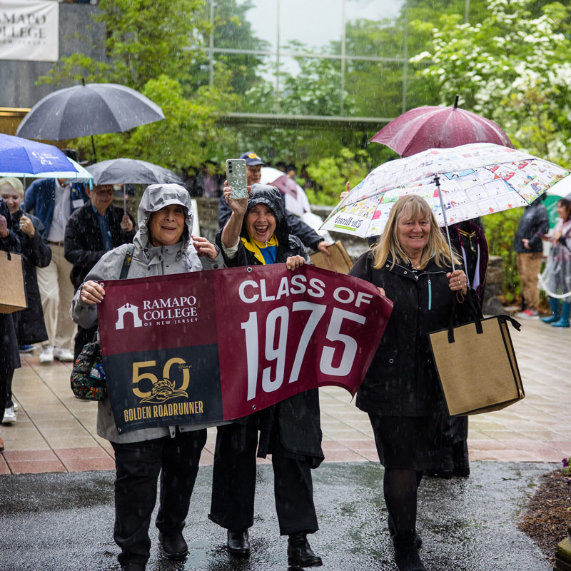 Three people holding a "Call of 1975" banner on a rainy day