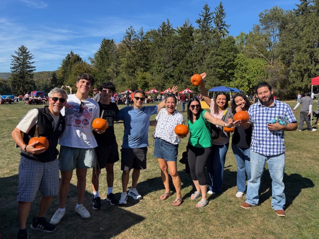 A group of Parents and students smiling holding pumpkins at Ramapo College's Homecoming event