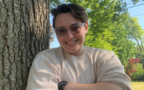 Lauren Marzano's headshot. She is leaning against a tree on her right side and has her arms folded across her chest.