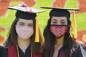 Two female RCNJ students wearing masks and regalia