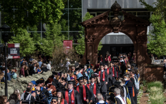 Ramapo College graduates walking through Arch in regalia during Arching ceremony