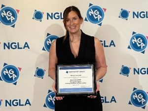 Amanda Riehl holds her Phillipi award in front of the NGLA step and repeat