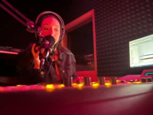 Student at sound board in radio station booth