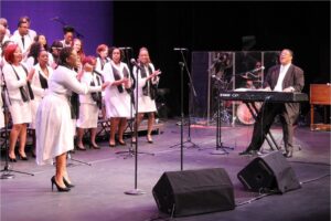 Mack Brandon and the Gospel Explosion chorus performing on stage.