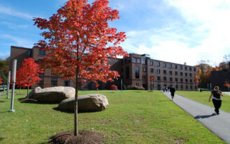 Image of Linden Hall , a brick building with fall trees in the foreground.