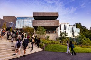 Students walking up and down the stairs in front of the Learning Commons building