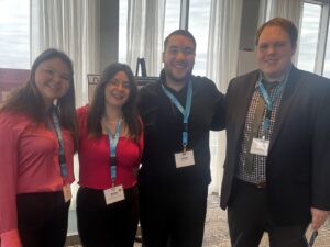 Sara, Melissa, Joseph, and William stand inside the ECA poster presentation room at the convention.