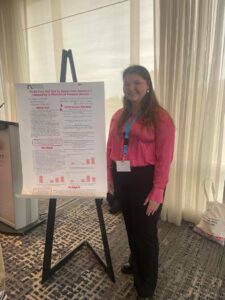Sara stands next to her research poster at the ECA conference
