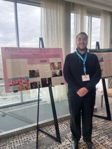 Joseph stands next to his research poster at the conference.