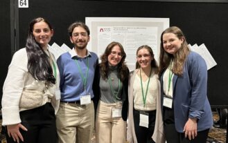 Five Ramapo students stand in front of an academic poster on display.